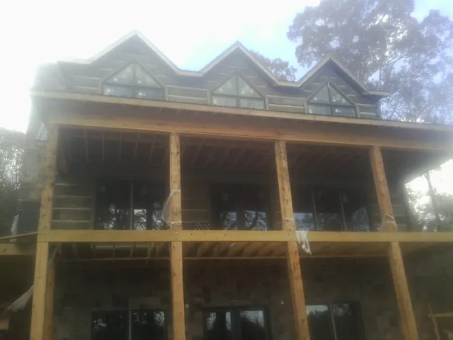 Dormers and porch framing on a large log home under construction — Roof Coating work by our crew in Rockville Centre