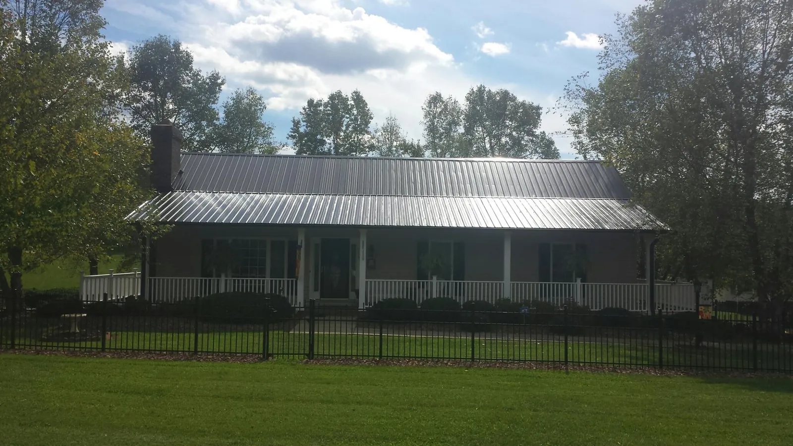 Gray metal roof on a brick ranch with a full width front porch — Gutter Guard Installation work by our crew in Rockville Centre