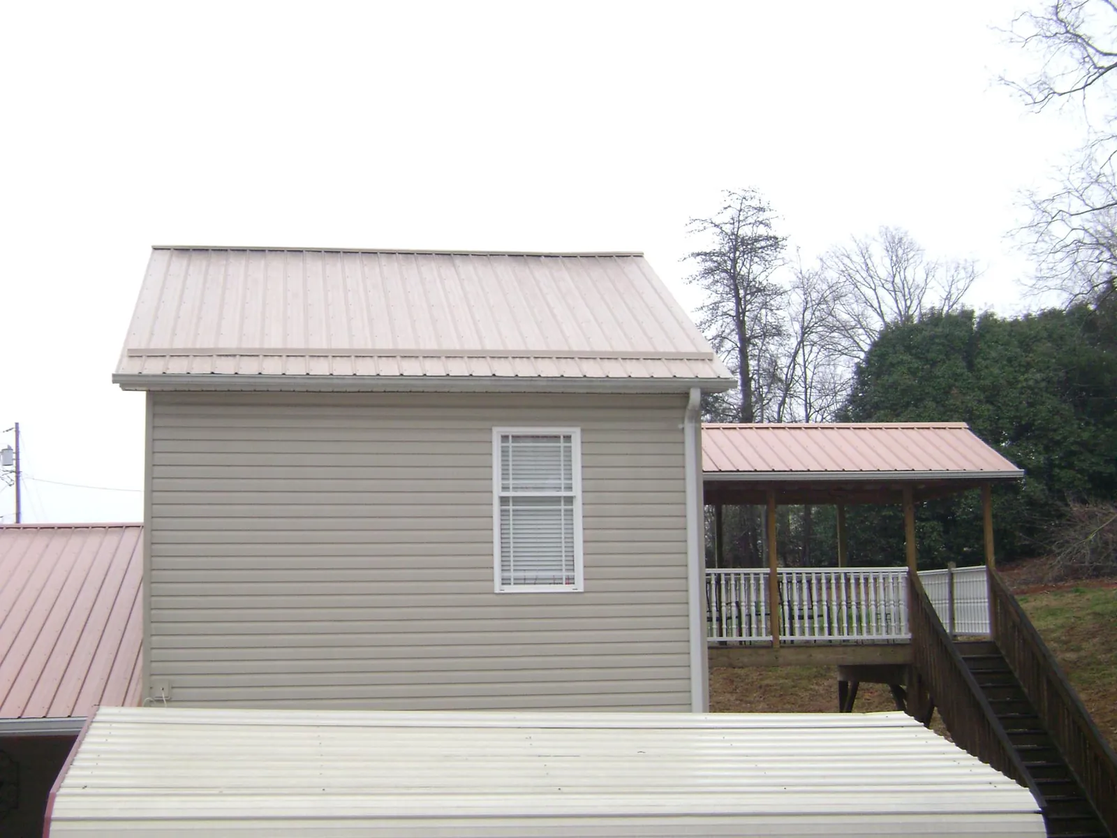 Tan metal roofs on a two story addition and attached porch, from a Roof Replacement job in Rockville Centre