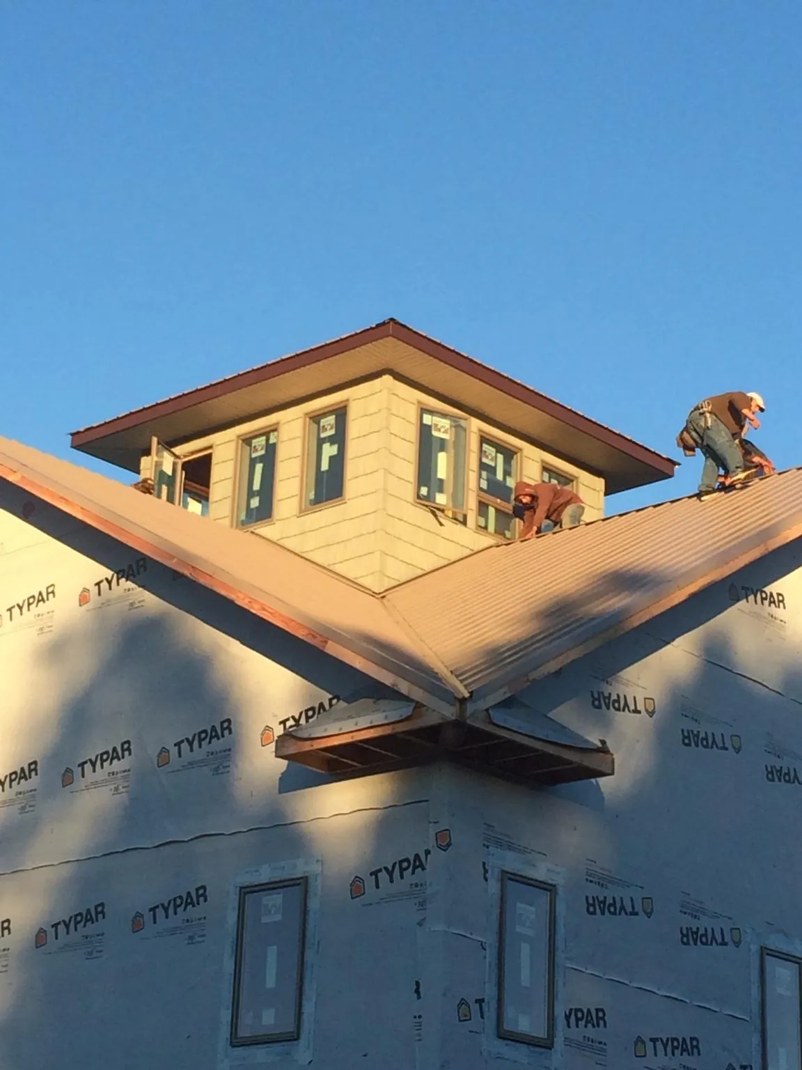 Roofers working around a rooftop cupola on a new metal roof at sunset — Roof Waterproofing in Rockville Centre by Roofing Brothers